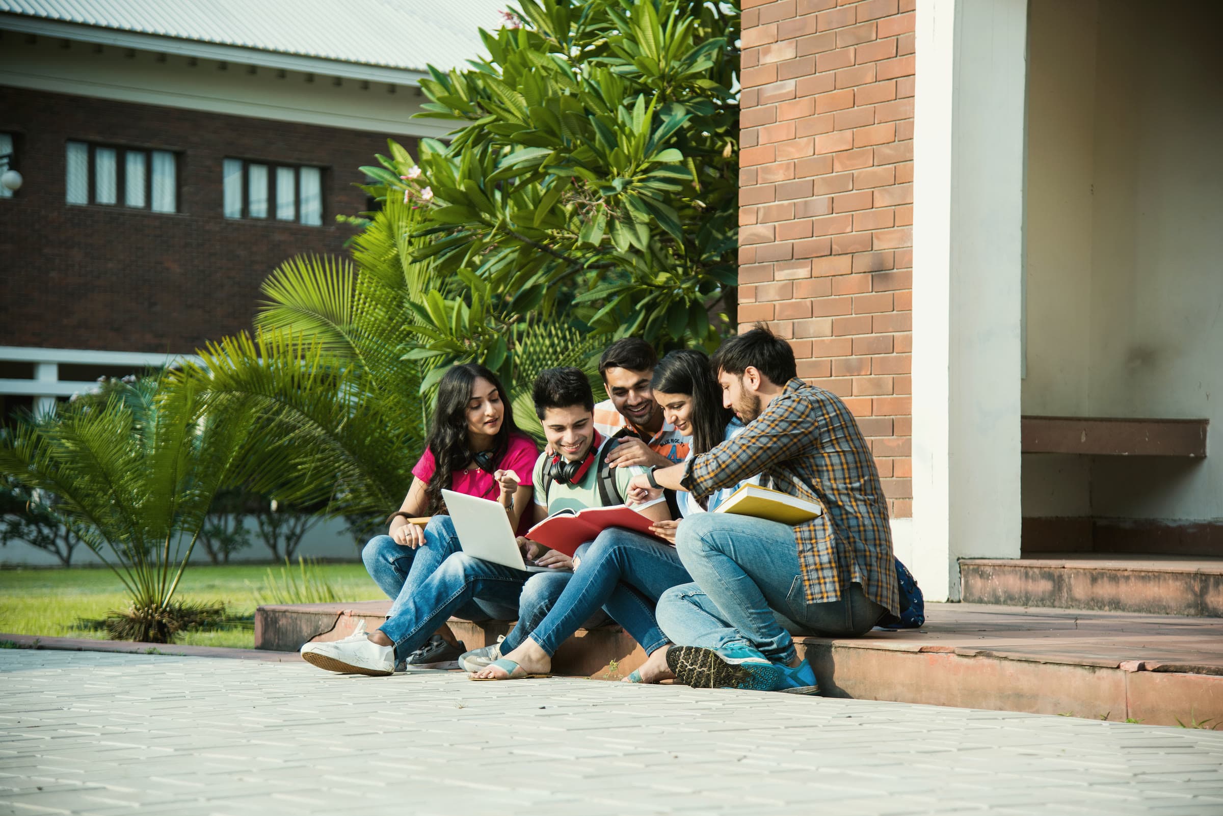 College students studying together on the steps outside a brick campus building